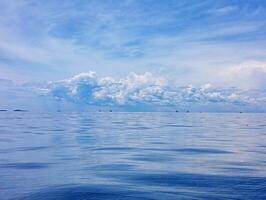 A blue sky with clouds and a boat in the water photo