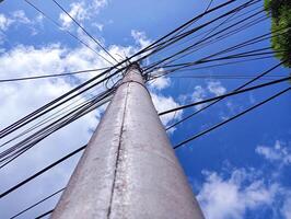 A tall pole with wires and a blue sky photo