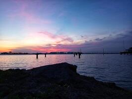A colorful sunset over the water with a pier in the foreground photo