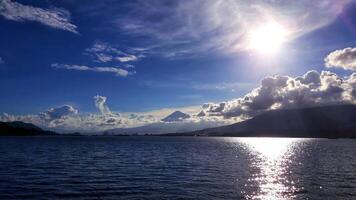 The sun shines brightly over a lake with mountains in the background photo