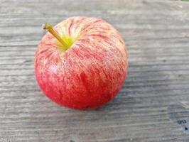 A red apple sitting on a wooden surface photo