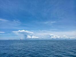 A blue sky with clouds and a boat in the ocean photo