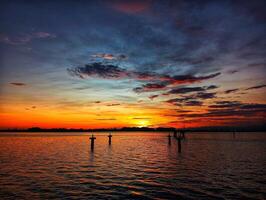 A sunset over the ocean with a boat in the water photo