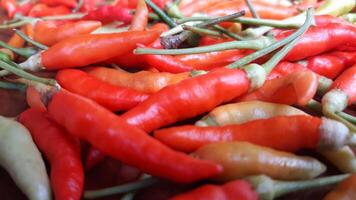A pile of red and orange peppers on a table photo