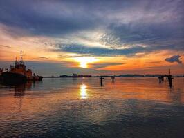 A boat is sitting in the water at sunset photo