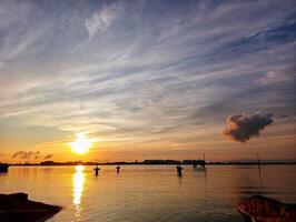 A sunset over the water with a boat in the distance photo