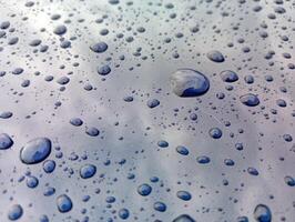 Water droplets on a glass surface with blue sky background photo