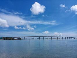 A bridge spanning the water with a blue sky photo