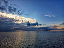 A boat is in the water with a cloudy sky photo