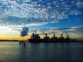 A large cargo ship is docked at sunset photo