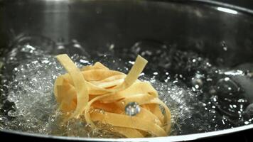 The tagliatelle pasta falls into the boiling water. Filmed on a high-speed camera at 1000 fps. High quality FullHD footage video