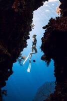 Woman freediver glides in underwater cave on Menjangan island, Bali. photo