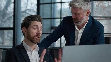 Caucasian men businessmen business partners looking computer screen in office coworkers argue shout because failed online project angry aggressive stressed man boss arguing with male employee conflict video