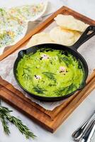 broccoli cream soup with herbs, cheese and tortillas in a frying pan, top view photo