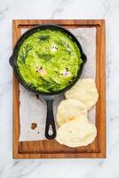 broccoli cream soup with herbs, cheese and tortillas in a frying pan, top view photo
