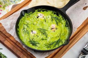 broccoli cream soup with herbs, cheese and tortillas in a frying pan, top view photo