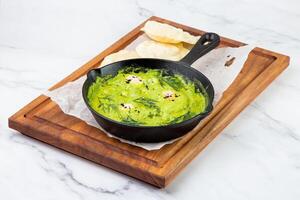 broccoli cream soup with herbs, cheese and tortillas in a frying pan, top view photo