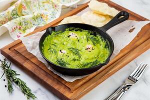 broccoli cream soup with herbs, cheese and tortillas in a frying pan, top view photo
