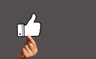 Customer service rating, satisfaction concept. Hand holding a thumbs up a symbol against a gray background photo