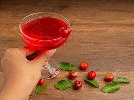 Hand holding a wine glass with cherry juice. photo