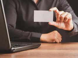 Close-up of hand a businessman in a black shirt holding a name card mockup while sitting in the office photo