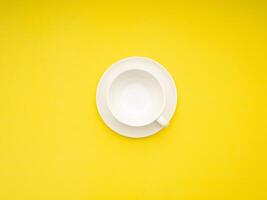 Top view of an empty white ceramic coffee cup on a yellow background photo