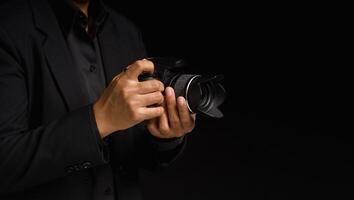 Close-up of hand holding the digital camera while standing on a black background photo