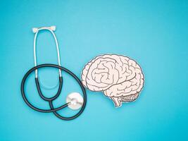 A stethoscope and brain shape made from paper over a blue background photo