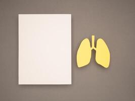 Lungs shape made from yellow paper and a blank white paper on a gray background photo
