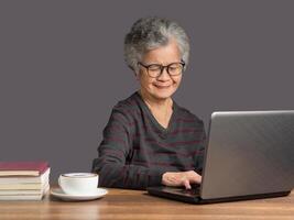 An elderly Asian woman using a laptop for searching data on the internet photo