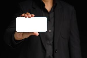 Hand holding a blank screen smartphone while standing on a black background photo