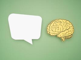 White speech bubble and a brain shape made from paper on a green background photo