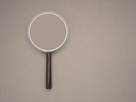 Top view of a magnifying glass on a gray background with space for text photo