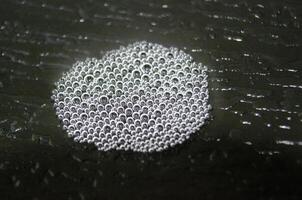 Top view of small bubbles clustered together on a dark background. photo