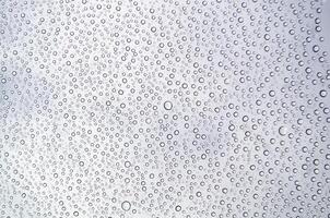 Close-up of droplets clustering on a glass surface after rain. Water texture concept photo