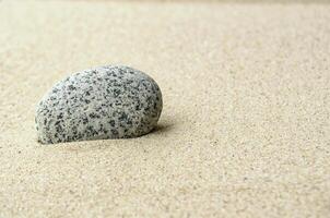 Single stone on beach sand with customizable space for text or ideas photo