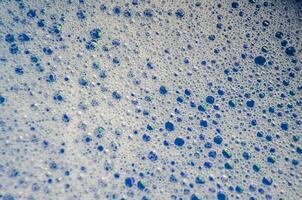 Macro view of bubbles forming on the water surface with blue background photo