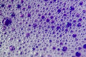 Macro shot of bubbles forming on a water surface with blue background photo