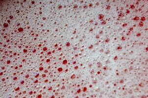 Macro view of bubbles forming on the water surface with red background photo