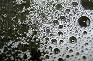 Macro view of bubbles forming on the water surface with dark background photo