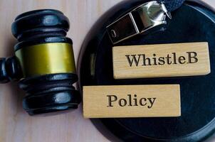 WhistleB Policy text engraved on wooden blocks with lawyer Gavel. Whistleblowing Law concept photo