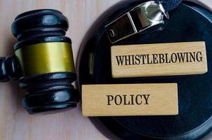 Whistleblower Policy text engraved on wooden blocks with lawyer gavel background photo