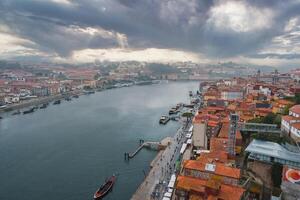 Stunning aerial view of Porto, Portugal, featuring the Douro River, Ribeira district, and Dom Luis I Bridge under a dramatic sky with sunlight rays. photo