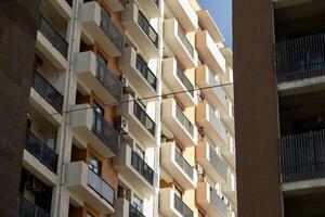 A tall building with windows, next to which workers stand on a crane. High quality photo