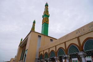 mosque tower with a combination of green and yellow. Mosque minaret against a cloudy sky background photo