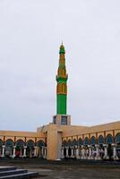 mosque tower with a combination of green and yellow. Mosque minaret against a cloudy sky background photo