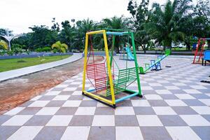 hanging swing chair that is usually found in parks or playgrounds. hanging swing chair made of iron with a combination of yellow, green, and red colors. photo