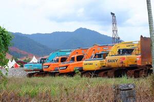 several excavators parked on the grassy ground photo