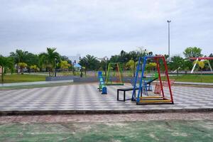 a playground in the park consisting of slides, seesaws, and hanging chairs. photo