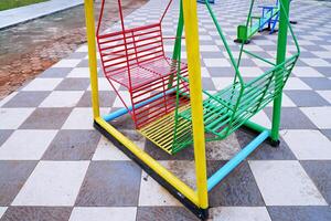 hanging swing chair that is usually found in parks or playgrounds. hanging swing chair made of iron with a combination of yellow, green, and red colors. photo